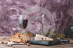 An assortment of various types of cheese with wine, and grapes, shot from above on a dark rustic background with a place