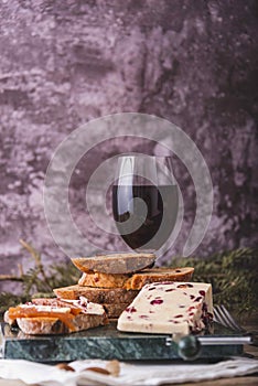 An assortment of various types of cheese with wine, and grapes, shot from above on a dark rustic background with a place