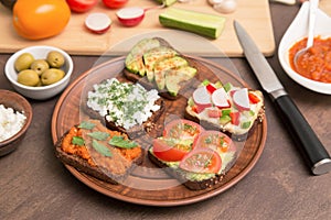 Assortment vegan, vegetarian sandwiches. Healthy homemade toasts with different vegetables and greens on plate close up