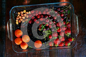 Assorty of fresh seasonal fruits and berries: strawberries, apricots, cherries, mulberry, raspberry washing under