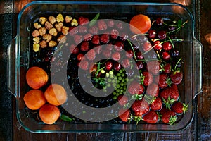 Assorty of fresh seasonal fruits and berries: strawberries, apricots, cherries, mulberry, raspberry washing under