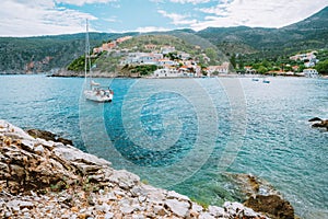 Assos cute town, on Kefalonia island, Greece. View of beautiful bay with sail yacht boat and mountains in background