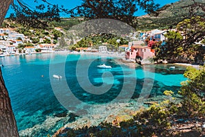 Assos village, Kefalonia, Greece. View on tourquise transparent water framed between green pine grove branches. Deep