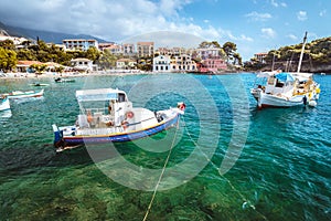 Assos village on Kefalonia island, Greece. White blue local boats at anchor in the emerald rippled sea water bay