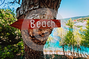 Assos village in morning light, Kefalonia. Greece. Beach wooden arrow sign on a pine tree showing direction to small