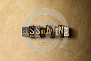 ASSUMING - close-up of grungy vintage typeset word on metal backdrop photo