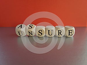 Assure or unsure symbol. Turned wooden cubes and changed the concept word unsure to assure. photo