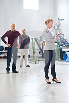 Assuring quality on the shop floor. A manager using a tablet during a factory inspection with her coworkers in the