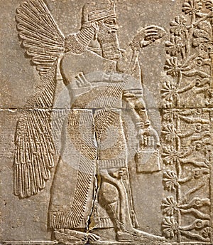 Assyrian wall relief of a winged genius with cuneiform