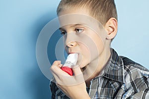 Asthma boy with is inhalator over blue background