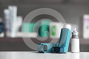 Asthma inhalers on table against blurred background.