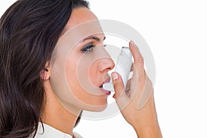Asthmatic brunette using her inhaler photo