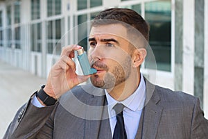 Asthmatic businessman using an inhaler at work