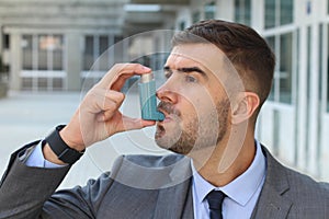 Asthmatic businessman using an inhaler at work