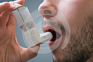 Asthmatic man suffers from asthma and is using inhaler