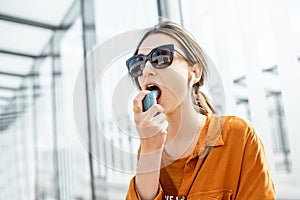 Asthmatic woman using inhaler outdoors photo