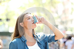 Asthmatic woman using inhaler standing in the street photo