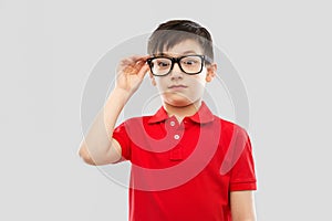 Astonished boy in glasses and red t-shirt goggling