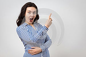 Astonished brunette girl pointing up