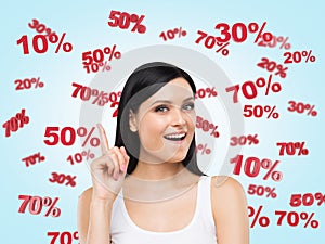 Astonished brunette surrounded by discount and sale numbers: 10% 20% 30% 50% 70%. photo