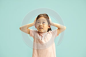 Astonished Chinese Child Girl Puts Hands on Head in Surprise and Looks up to Empty Copy Space Expression Amazement