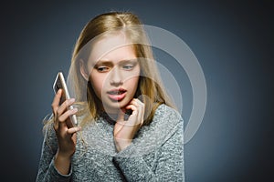 Astonished cute girl with cell phone. isolated on gray