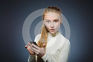 Astonished cute redhead girl with cell phone. isolated on gray