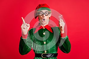 Astonished elf raise finger up hold light bulb clever think concept wear green costume isolated on red shine color