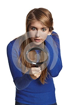 Surprised woman looking through the magnifying glass downwards