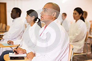 Astonished hispanic doctor listening to lecture at refresher course