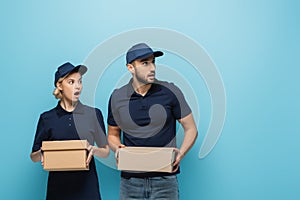 astonished multicultural couriers looking away while