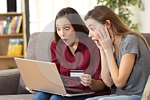 Astonished roommates buying on line at home photo