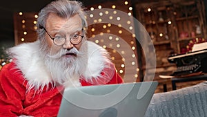 Astonished Santa Claus receiving email wishlist use laptop. Medium close up shot on 4k RED camera