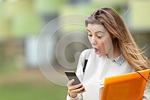 Astonished student receiving news on a smart phone