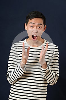 Astonished young Asian man gesturing with two hands