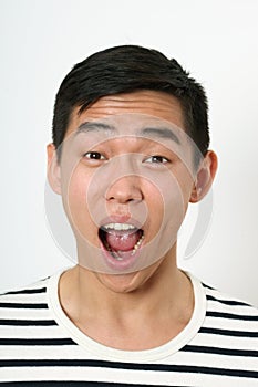 Astonished young Asian man looking at camera