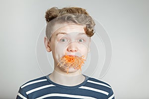 Astonished young boy with a mouthful of carrot photo