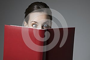Astonished Young Female Reading Book With Eyes Wide Open photo