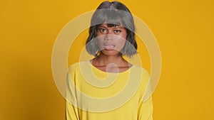 Astonished young woman looks amazement stares disbelief over yellow background