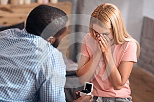 Astonished young woman receiving engagement ring at home