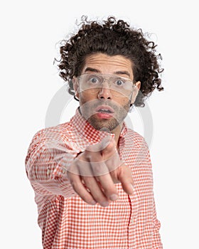 astounded casual man with glasses looking forward and pointing finger