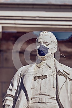 Astrakhan / Russia - May 29, 2020: Monument to one of the Bolshevik revolutionaries Kirov in a medical mask. Park in the