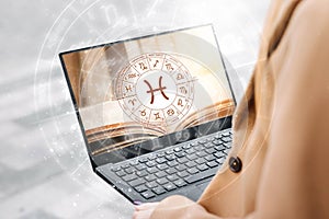 Astrological forecast for the zodiac sign Pisces. Woman holding an open laptop with a picture of a book and the zodiac