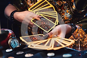 Astrology and cartomancy. A fortune teller holds a fan of Tarot cards. On the table are runes. Close-up of hands