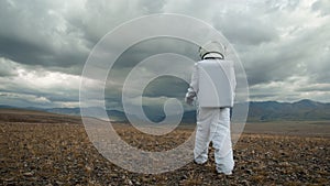 An astronaut explores an unknown planet. Cloudy sky
