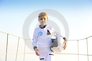 Astronaut futuristic kid girl with white full length uniform and helmet wearing silver shoes outdoors