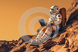 Astronaut with laptop sitting on rocky Mars-like terrain.