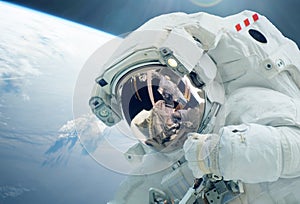 The astronaut in an outer space, against the background of the earth. Elements of this image were furnished by NASA