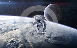 Astronaut in outer space against the background of the Earth`s landscape and the Moon. Solar system. Science fiction