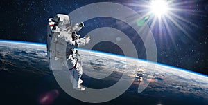 Astronaut in outer space on orbit of Earth planet. Sky and clouds. Spacewalk with stars